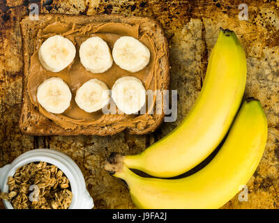 Tranches de banane et beurre d'arachide sur farine de pain grillé sur un plateau de four Banque D'Images