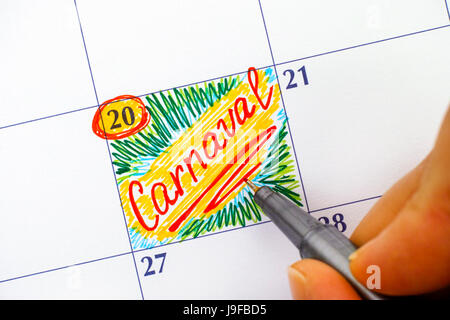 Femme doigts avec stylo rouge écrit Carnaval rappel dans le calendrier. Banque D'Images