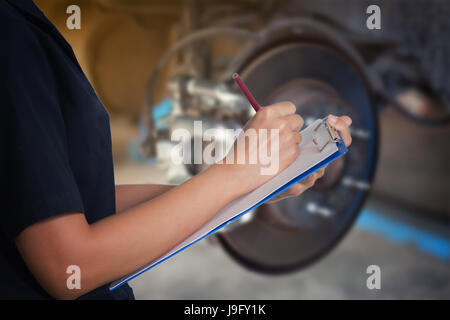 Les femmes asiatiques sont les ingénieurs et techniciens de contrôle et d'inspection mécanique sur un disque de frein de roue de voiture et les chaussures de service de réparation automobile à la levée Banque D'Images