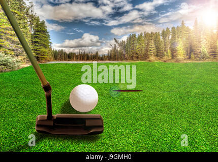 À l'aide d'un club de golf putter pour frapper une balle de golf sur un magnifique parcours de golf avec des lacs et des paysages de montagne tôt le matin. Dissémination volontaire des reflets. Banque D'Images