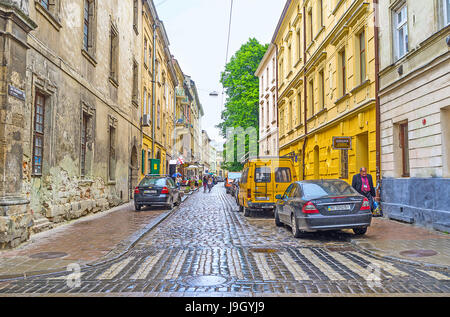 LVIV, UKRAINE - 16 MAI 2017 : les maisons minables dans la rue de la vieille ville, le temps pluvieux rend le pavé humide et brillant, le 16 mai à Lviv. Banque D'Images