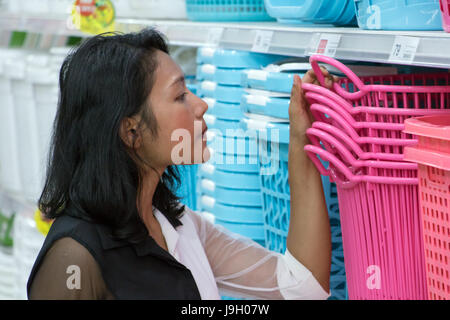 Portrait de jeune femme dans un supermarché. Vêtements femme choisit asiatique panier des étagères au Mall. Banque D'Images