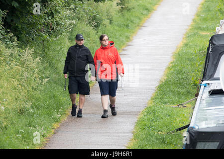 Un couple en train de marcher en short et manteaux de pluie le long d'un canal toe chemin sur un jour de pluie le long du Canal, l'Union shopshire Sandbach Banque D'Images