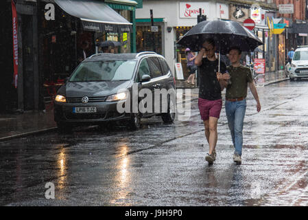 Soho, London, UK. Le 2 juin 2017. Deux hommes partagent un parapluie comme l'un des orages prédit par le Met Office passe sur Old Compton Street à Soho, Londres. Crédit : Paul Davey/Alamy Live News Banque D'Images