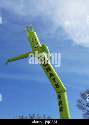 Faites un don ici inflatable cute cartoon character dancing against blue sky Banque D'Images