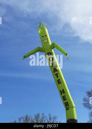 Faites un don ici inflatable cute cartoon character dancing against blue sky Banque D'Images