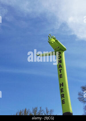 Faites un don ici inflatable cute cartoon character dancing against blue sky Banque D'Images