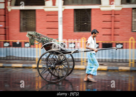 Vie de l'Inde avec Rickshaw wala sur le Manuel des rues humides de Kolkata. L'un des derniers bastions de ce travail non qualifiés tirant un rickshaw en Inde Banque D'Images