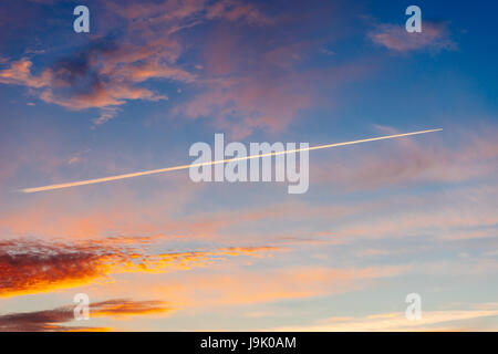 Trace d'avion dans le ciel dramatique sur le coucher du soleil. Traînée de vapeur de carburant des compagnies aériennes dans la soirée cloudscape Banque D'Images