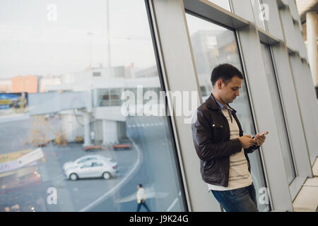 Jeune homme d'affaires dans la région de airport en utilisant smartphone . Banque D'Images