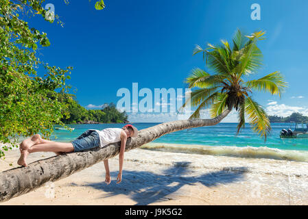 Cute boy resting allongé sur un palmier tropical island le vacationю Banque D'Images