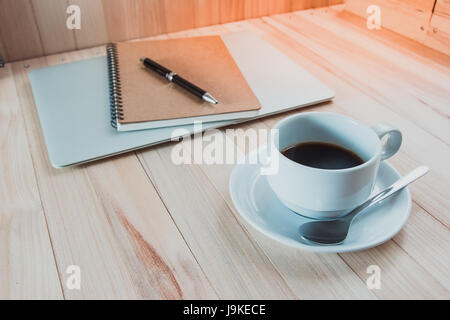 Tasse de noir chaud coffec mettre près de bloc-notes numérique, stylo mis sur ordinateur, arrêter de travailler avec la pause café de bureau moderne. Banque D'Images