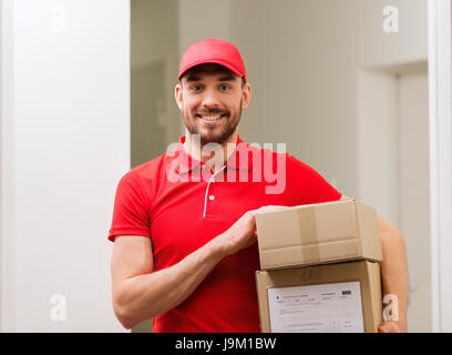 Delivery man avec boîtes à colis in corridor Banque D'Images
