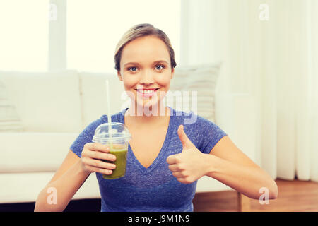 Happy woman with cup du smoothie showing Thumbs up Banque D'Images