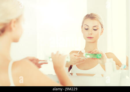 Jeune femme avec une lotion visage à laver salle de bains Banque D'Images