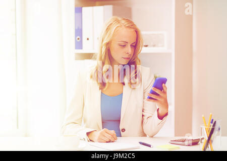Businesswoman texting on smartphone at office Banque D'Images
