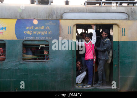 Gens en suspens aux portes ouvertes de commuter train passant par la gare de New Delhi en Inde Banque D'Images