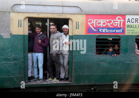 Gens en suspens aux portes ouvertes de commuter train passant par la gare de New Delhi en Inde Banque D'Images