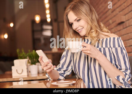 Young woman text messaging while having coffee Banque D'Images