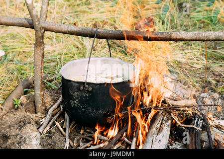 Ancienne rétro Camp Casserole de l'eau bouillie pour la préparation de la Soupe sur le feu en forêt. Flamme Feu Feu à jour d'été . Banque D'Images