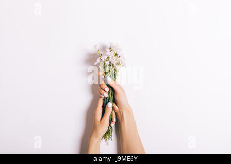 Belle femme avec les mains manucure tenir un bouquet de petites roses sur fond blanc, close-up Banque D'Images