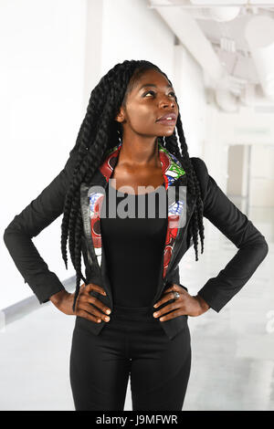 Young African American businesswoman looking up avec les mains sur les hanches à l'intérieur office Banque D'Images