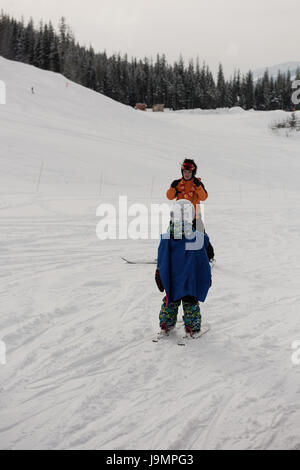 Petit garçon l'apprentissage du ski avec moniteur sur pente enneigée dans station de ski Banque D'Images