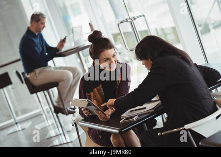 Des collègues discuter sur digital tablet in office cafeteria Banque D'Images
