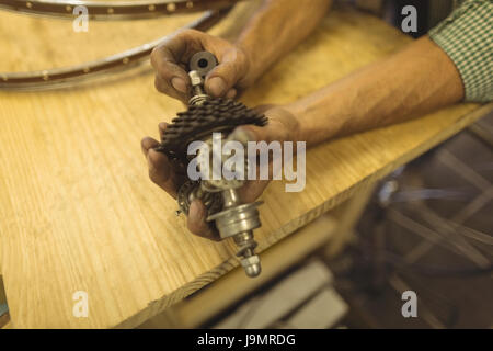 Les mains coupées de travailleur la réparation bicycle gear sur table d'atelier Banque D'Images