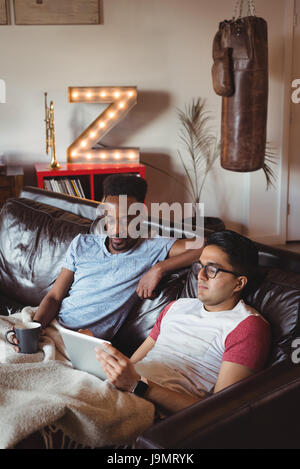 Gay couple assis sur un canapé à la maison Banque D'Images