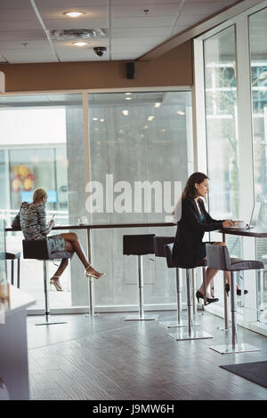 Two businesswomen working in office cafeteria Banque D'Images