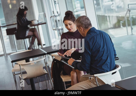 Des collègues discuter sur digital tablet in office cafeteria Banque D'Images