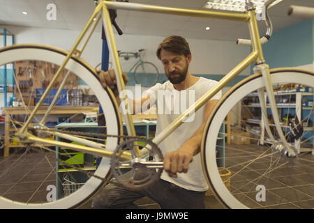 Travailleur sérieux câblages vintage bicycle en atelier Banque D'Images