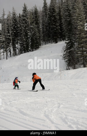 Petit garçon l'apprentissage du ski avec moniteur sur pente enneigée dans station de ski Banque D'Images