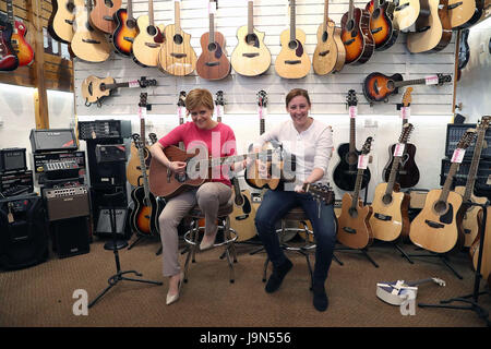 Premier ministre Nicola Sturgeon (à gauche) est montré comment jouer une guitare par le candidat local SNP Mhairi noir tandis que sur la campagne électorale générale trail à Paisley. Banque D'Images