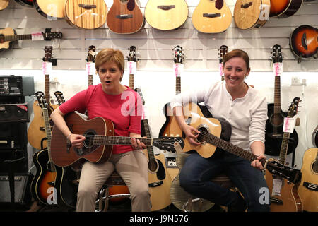 Premier ministre Nicola Sturgeon (à gauche) est montré comment jouer une guitare par le candidat local SNP Mhairi noir tandis que sur la campagne électorale générale trail à Paisley. Banque D'Images