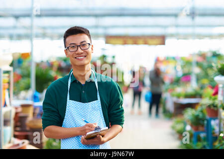 Un jeune homme asiatique boutique Fleuriste travaillant dans l'usine ou avec de nombreuses fleurs tout autour Banque D'Images