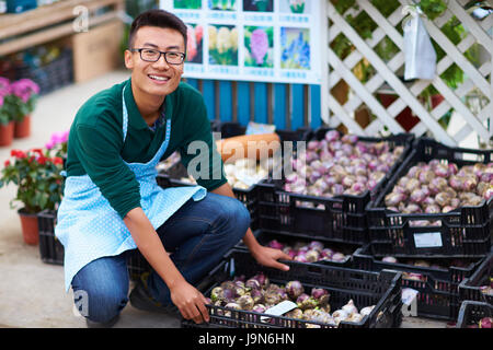 Un jeune homme asiatique boutique Fleuriste travaillant dans l'usine ou avec de nombreuses fleurs tout autour Banque D'Images