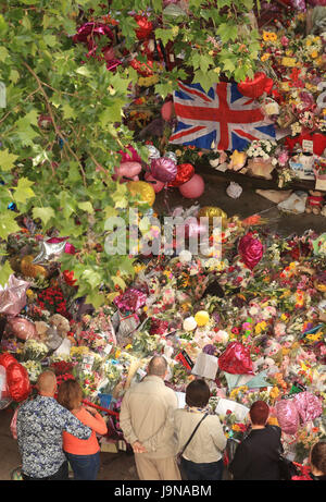 Les gens regardent les fleurs et hommages à gauche dans St Ann's Square à Manchester Manchester Arena suite à l'attaque terroriste. Banque D'Images