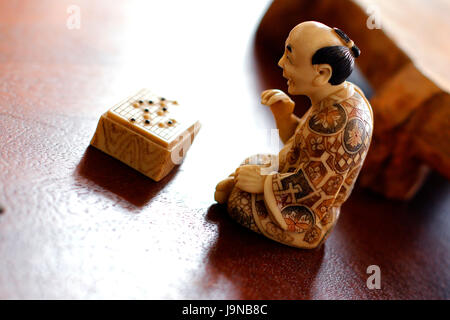 Un petit soft sculpture de marbre art de l'ancien moine japonais ou chinois jouant aux échecs chinois jeu de société sur table en bois avec belle rétro-éclairée. Banque D'Images