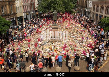 Les gens regardent les fleurs et hommages à gauche dans St Ann's Square à Manchester Manchester Arena suite à l'attaque terroriste. Banque D'Images