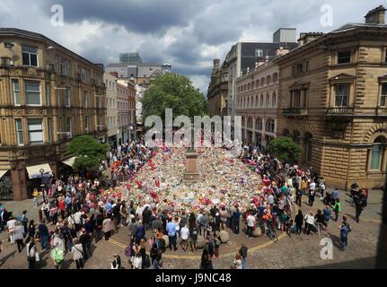 Les gens regardent les fleurs et hommages à gauche dans St Ann's Square à Manchester Manchester Arena suite à l'attaque terroriste. Banque D'Images