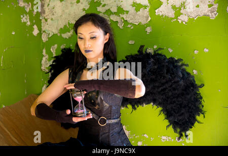 Jeune femme à l'intérieur d'une maison abandonnée avec une heure d'horloge le temps Banque D'Images