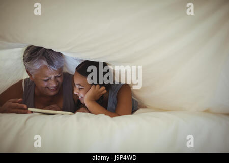 Grand-mère et petite-fille using digital tablet in bed room à la maison Banque D'Images