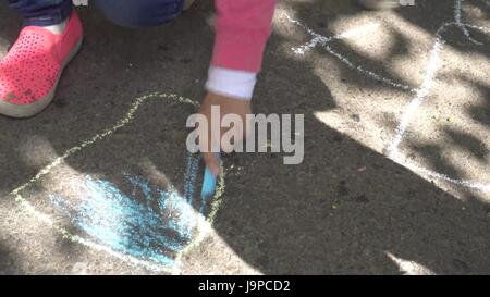 Dessin à la main de bébé avec les craies de couleur sur la chaussée Banque D'Images