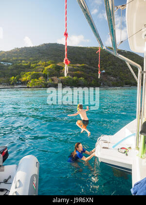 Un enfant saute dans les eaux turquoise de l'arrière d'un catamaran dans les îles Vierges britanniques Banque D'Images