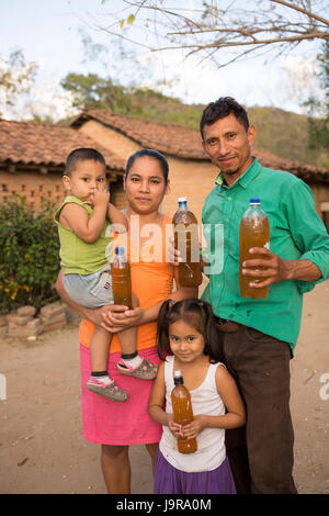 Une famille d'éleveurs d'abeilles bouteilles de hold-fraîchement récolté le miel dans Léon, Ministère du Nicaragua. Banque D'Images