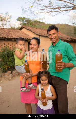 Une famille d'éleveurs d'abeilles bouteilles de hold-fraîchement récolté le miel dans Léon, Ministère du Nicaragua. Banque D'Images