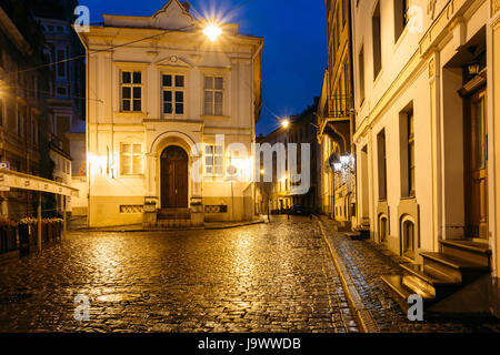 Riga, Lettonie - Juillet 3, 2016 : Ancien bâtiment à l'intersection de la Maza Pils et Klostera rues en soirée ou la nuit Illuminations Lumières en Vieille Ville Banque D'Images