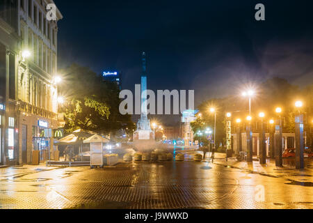 Riga, Lettonie - 4 juillet 2016 : Night View Of Memorial Monument de la liberté à la place de la liberté et l'horloge Laima éclairage dans l'éclairage de nuit. Vue depuis Kalku Banque D'Images